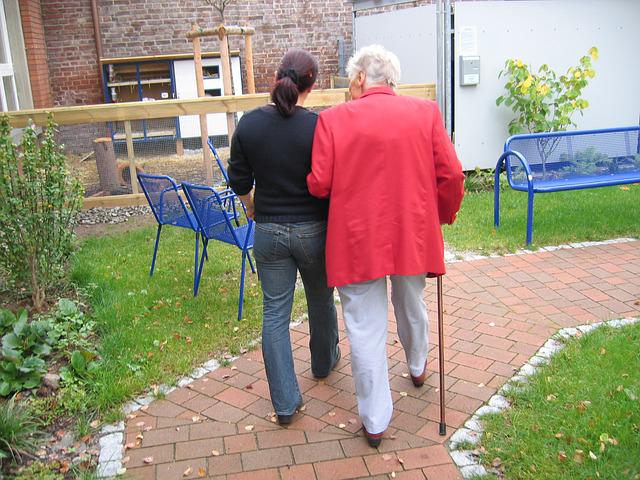 Oudere dame en verzorger aan het wandelen