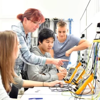Groep werknemers en leerlingen krijgt instructie van begeleider over het werken met verschillende apparaten en systemen, aangekocht met behulp van subsidieadvies.
