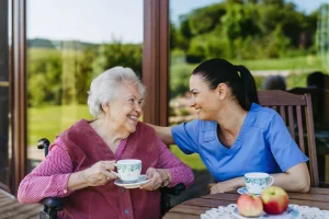 Afbeelding met seniore dame en verzorgende die koffie drinken, subsidie Stagefonds Zorg