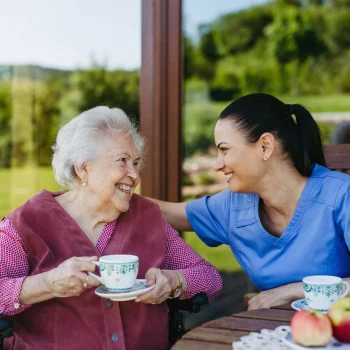 Afbeelding met seniore dame en verzorgende die koffie drinken, subsidie Stagefonds Zorg
